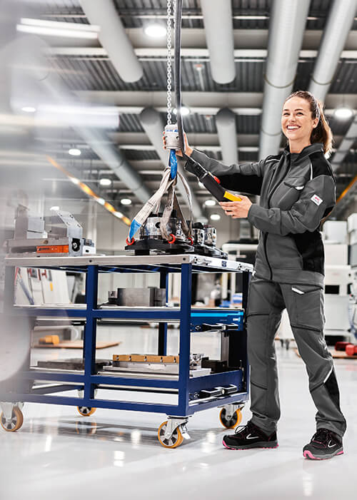 Eine Frau in Arbeitskleidung von Kübler in einer Werkstatt an einer Werkbank.