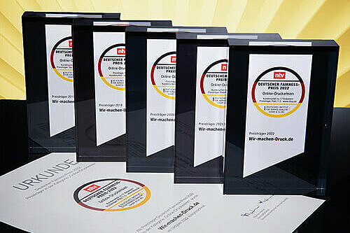 Die fünf Pokale des Deutschen Fairness-Preises in einer Reihe. Darunter liegt eine Urkunde.