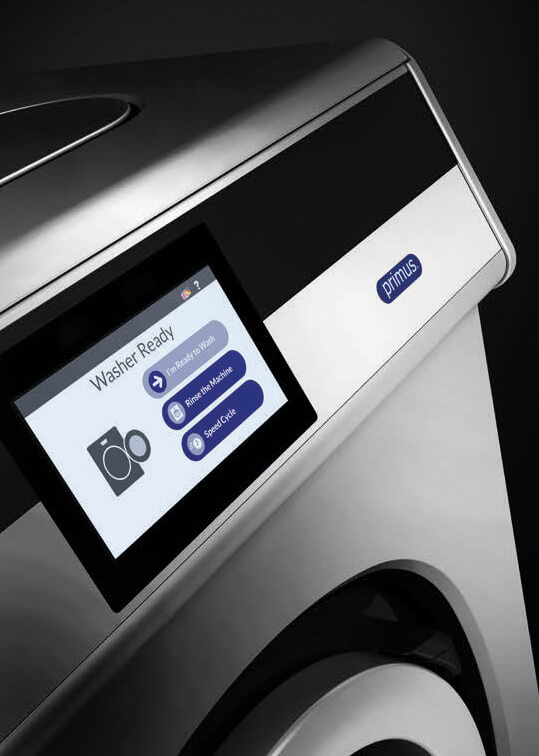 Detailansicht der Steuerung einer Waschschleudermaschine aus der FX-Reihe von Primus. Auf dem Display steht: "Washer Ready". Darunter stehen drei Buttons: "I'm ready to Wash", "Rinse the Machine" und "Speed Cycle". Links daneben wird ein Icon mit einer offenen Waschmaschine angezeigt.