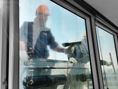Blick von innen durch ein modernes Fenster, das von außen von Personen in Arbeitskleidung gereinigt wird