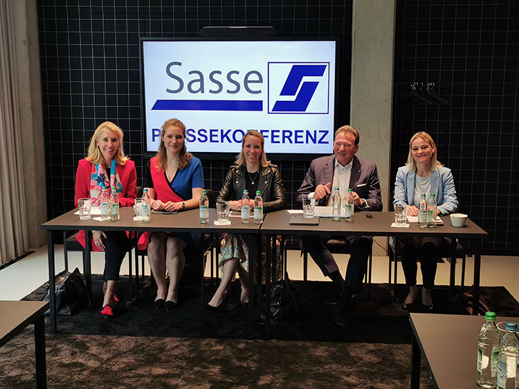 Vorstandsmitglieder Dr. Christine Sasse, Clara Sasse, Dr. Laura Sasse Eberhard Sasse und Katja Böhmer auf der Pressekonferenz der Dr. Sasse AG 2022. Die Personen sitzen nebeneinander an einem Konferenztisch und lächeln in die Kamera. Auf einem Bildschirm hinter ihnen ist das Sasse-Logo und der Schriftzug "Pressekonferenz" zu sehen.